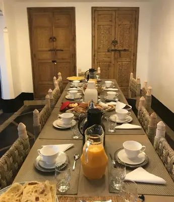 a long table with plates and cups and orange juice at Riad Bab aylen - Piscine Roof Top chauffée in Marrakech
