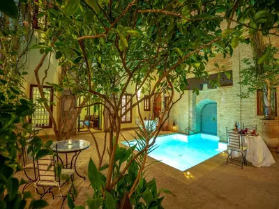 a pool with a table and chairs and a tree at Riad Il Parco dei Principi in Marrakech