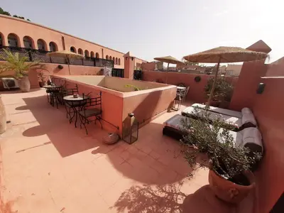 an outdoor patio with tables and chairs and an umbrella at RIAD PÉNÉLOPE Marrakech in Marrakech