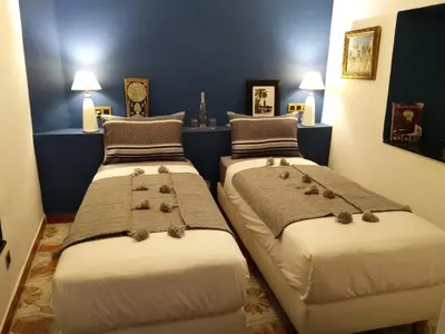 two beds in a room with blue walls at Riad Bilkis Votre Maison Marrakech in Marrakech