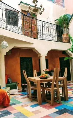 a dining room with a table and chairs and a balcony at Riad Bilkis Votre Maison Marrakech in Marrakech