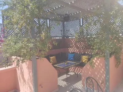 a patio with a table and chairs under a pergola at appartment achwaq in Marrakech