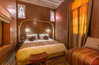 a bedroom with a bed and a chair in a room at Riad AZARO in Marrakech