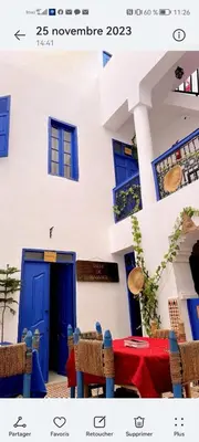 a house with a blue door and a table with chairs at RIAD DAR LFONOUN in Marrakech
