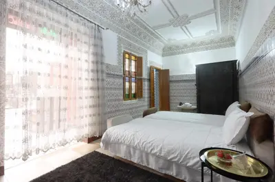 a bedroom with a large bed and a table at Riad Dwiriyat My Teib in Marrakech