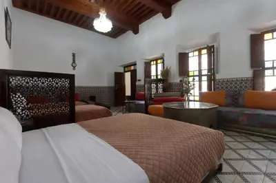 a bedroom with two beds and a living room with a couch at Riad Dwiriyat My Teib in Marrakech