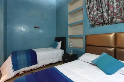 two beds in a room with blue walls at Riad Dwiriyat My Teib in Marrakech