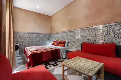 a living room with a red couch and a bed at Riad Dwiriyat My Teib in Marrakech