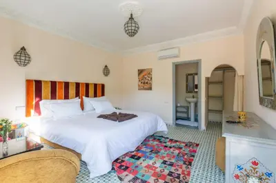 a bedroom with a white bed and a rug at Riad les deux citronniers in Marrakech