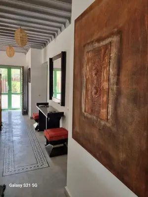 a large painting on the wall in a room with a piano at Riad les deux citronniers in Marrakech