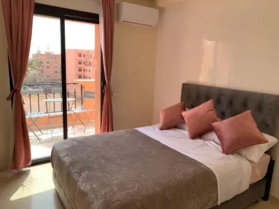 a bedroom with a bed with a view of a balcony at Victor hugo Appartement in Marrakech