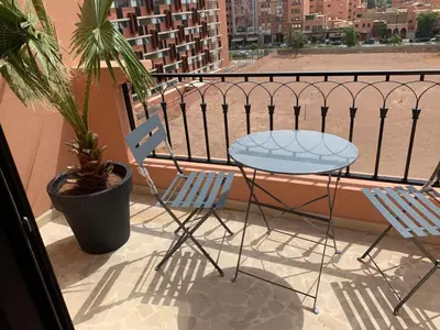 a balcony with a table and chairs on a balcony at Victor hugo Appartement in Marrakech