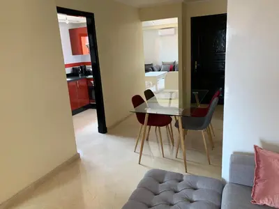 a living room with a glass table and chairs at Victor hugo Appartement in Marrakech