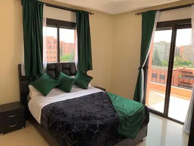 a bedroom with a bed with green pillows and a window at Victor hugo Appartement in Marrakech