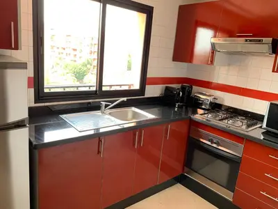 a kitchen with red cabinets and a sink and a window at Victor hugo Appartement in Marrakech