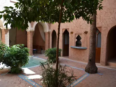 a courtyard of a building with a fountain and trees at Riad Zahir in Marrakech