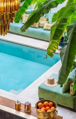 a bowl of oranges on a table next to a pool at Riad Tajania in Marrakech