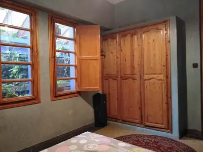 a bedroom with wooden cabinets and two windows at Dar Rmila 4 in Marrakech