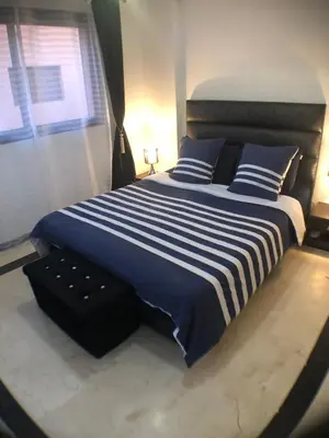 a bedroom with a large bed with blue and white stripes at Annakil Appart in Marrakech