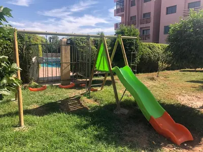 a playground with a slide in the grass at Annakil Appart in Marrakech