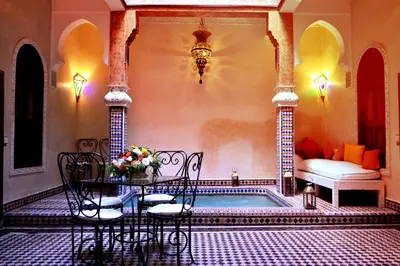 a room with a table and chairs next to a pool at Riad Charik in Marrakech