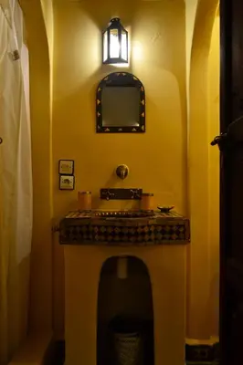 a yellow bathroom with a sink and a mirror at Riad Charik in Marrakech