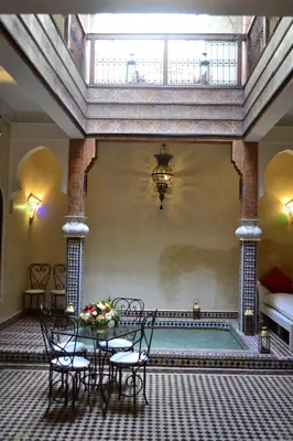 a room with a pool with chairs and a table at Riad Charik in Marrakech