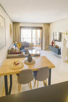 a living room with a table and a couch at Apt standing 80m2, 2 chambres, terrasse, piscine in Marrakech