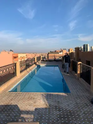 a man walking on top of a building with a swimming pool at Apt standing 80m2, 2 chambres, terrasse, piscine in Marrakech