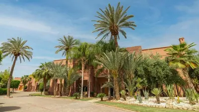 a building with palm trees in front of it at Mimouna Riads in Marrakech
