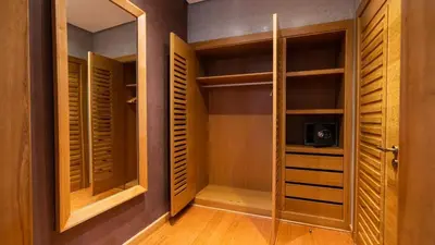 a walk in closet with wooden cabinets and a glass door at Mimouna Riads in Marrakech