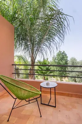 a hammock and a table on a balcony with a palm tree at Villa Cosy - Jardin de l'Atlas - Golf & Waky in Marrakech