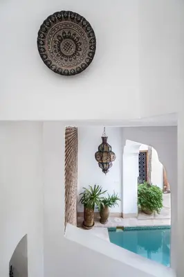 a room with a pool and a plate and plants at Riad El Maktoub in Marrakech