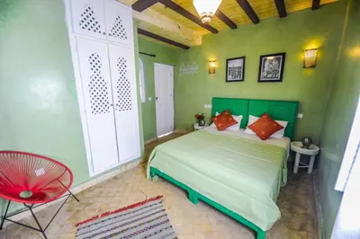 a bedroom with a green bed and a red chair at Riad Milouda in Marrakech
