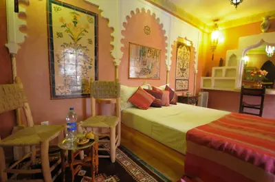 a bedroom with a bed and a table and chairs at Riad Basma Marrakech in Marrakech