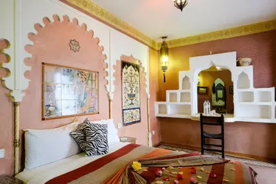 a bedroom with a bed and a table and a mirror at Riad Basma Marrakech in Marrakech