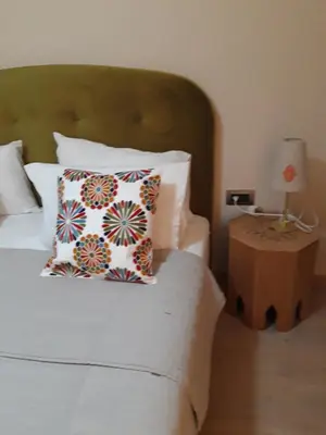 a bed with a pillow and a table with a lamp at Jade Golf City in Marrakech