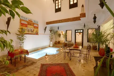 a living room with a pool and a table and chairs at Riad Capri in Marrakech