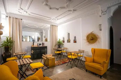 a living room with yellow chairs and a table at Riad Come & Va Medina in Marrakech