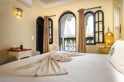 a bedroom with a large white bed with windows at Riad Come & Va Medina in Marrakech