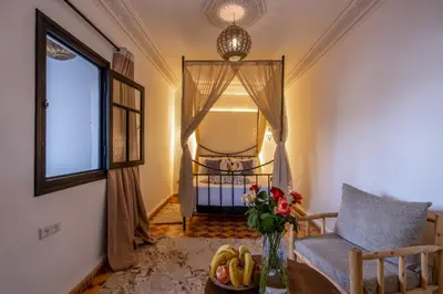 a living room with a table and a chair and a window at Riad des remparts Marrakech in Marrakech
