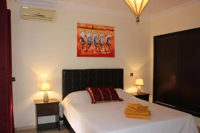 a bedroom with a bed and two lamps and a painting at Studio Salmiya Dune in Marrakech