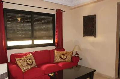 a red couch in a living room with a window at Studio Salmiya Dune in Marrakech