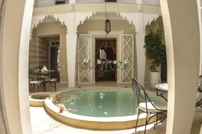 a pool in a building with chairs and a table at Riad THALGE in Marrakech