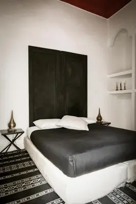 a bedroom with a large bed with a black headboard at Riad THALGE in Marrakech