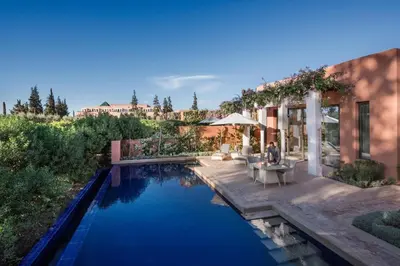 a swimming pool with a table and chairs next to a house at The Oberoi Marrakech in Marrakech