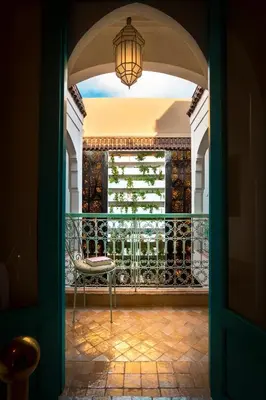 an open door to a balcony with a chair and a chandelier at Riad Lumière in Marrakech