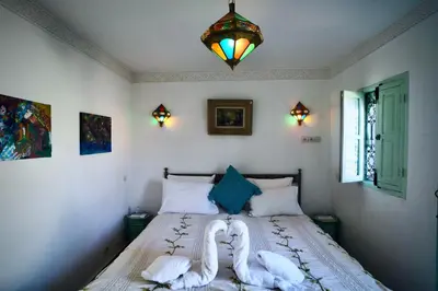 a bedroom with a bed with white sheets and a chandelier at Riad Lumière in Marrakech