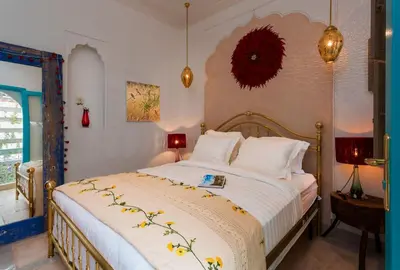 a bedroom with a large bed with white sheets at Riad Lumière in Marrakech