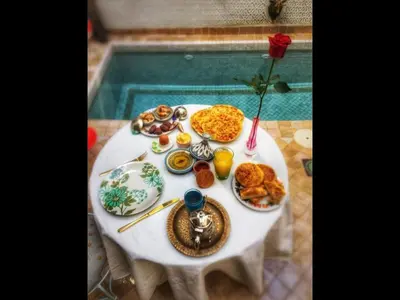 a table with breakfast foods on it next to a pool at Riad Lumière in Marrakech